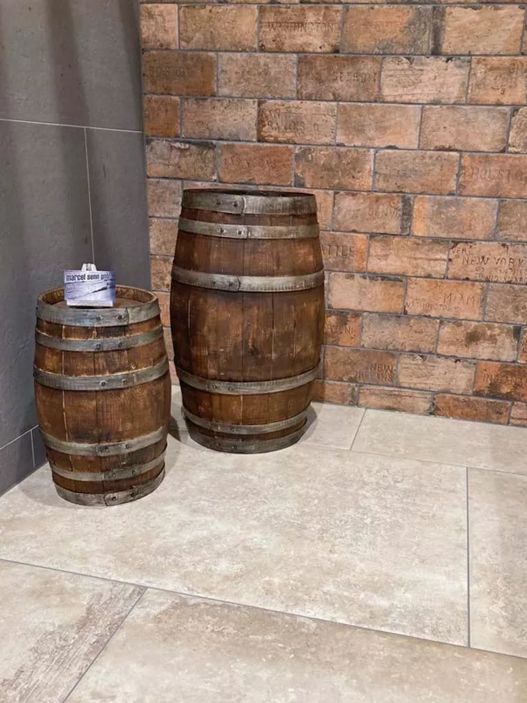 Zwei naturbelassene Weinfässer aus Eichenholz vor einer Backsteinwand in einem Showroom