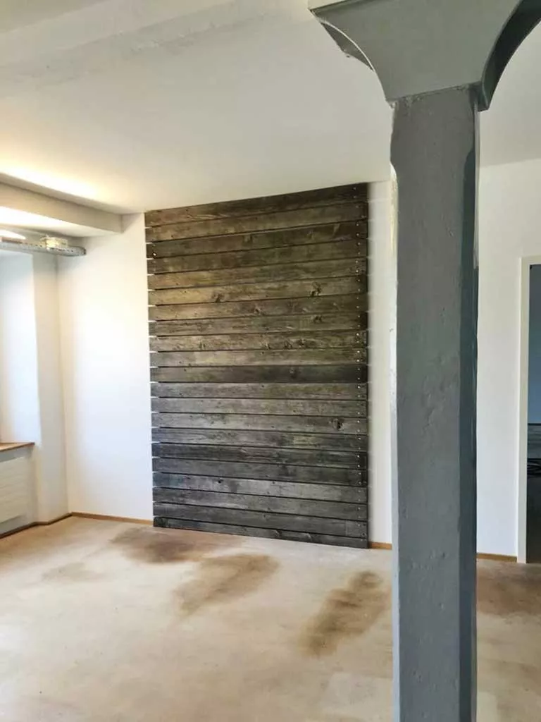 Dekowand aus naturbelassenem Altholz als Raumabgrenzung in einem Showroom